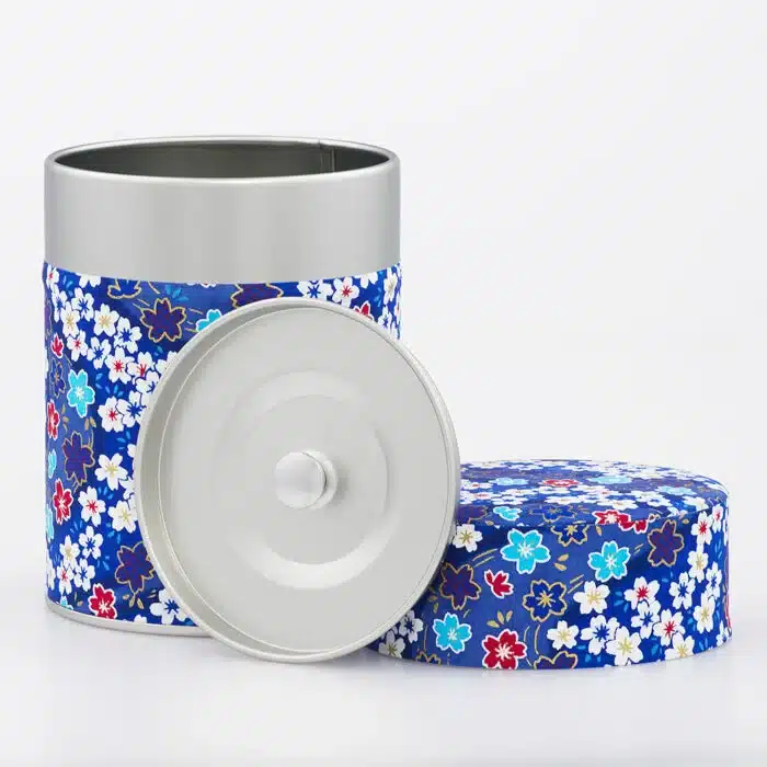 Opengeklapte Yokote theekist, met de twee metalen deksels en het kleurrijke Japanse washi papierontwerp